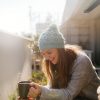 Photo of a two young women taking a few minutes off to relax and drink coffee on the balcony, on a beautiful, sunny, autumn day